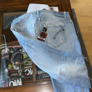 Ljusblå donpud jeansbyxor - Säljer ett par ljusblå jeansbyxor med en klassisk femficksdesign är 34 vid vid midja men passar 32. Byxorna har en rak passform och är tillverkade i denim. Perfekta för en avslappnad stil. Passa på köp innan dom slängs  en parfym ingår 😁