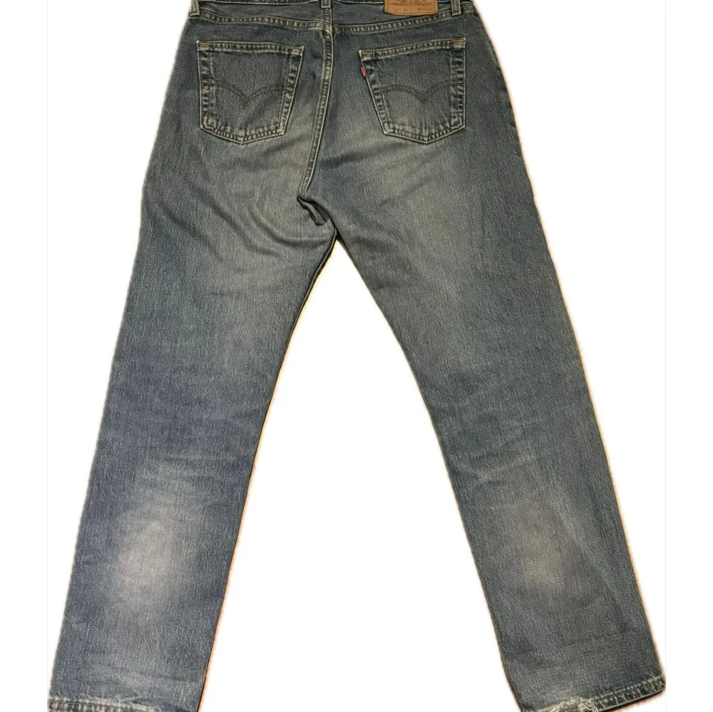 Säljer ett par klassiska Levi's 517 jeans i blå denim. Dessa jeans har en rak passform och är tillverkade i slitstarkt jeansmaterial. Perfekta för en avslappnad stil. Har slitningar vid ena knät och längst ner. Storlek w33l32. Farkut & Housut.