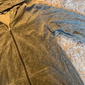 Grå hoodie med dragkedja - Säljer en grå hoodie med dragkedja och huva. Den har långa ärmar och praktiska fickor framtill. Perfekt för en avslappnad stil.