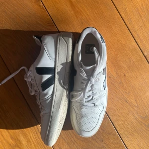 Vita sneakers från Veja - Snygga vita sneakers från Veja med svarta detaljer. Skorna har en klassisk design med snörning och en bekväm sula. Perfekta för en stilren look.
