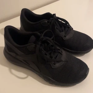 Svarta Reebok skor  - Snygga och bekväma svarta Reebok skor med snörning. Perfekta för vardagsbruk och träning. Skorna har en stilren design med en slitstark sula och andningsbart material. 