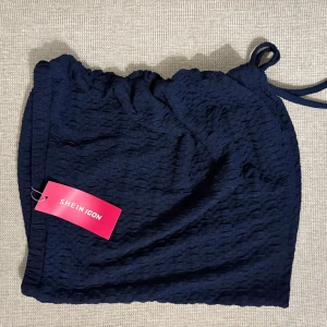 Mörkblå omlottkjol och topp från SHEIN - Säljer en mörkblå kort omlottkjol och topp från SHEIN med knyt i sidan. Sette har en lätt strukturerad yta och är perfekt för dig som gillar en enkel men trendig stil. Passar till många olika looks och är superenkel att matcha.