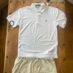 Helt ny vit pikétröja från Polo Ralph Lauren - Klassisk vit pikétröja från Polo Ralph Lauren med krage och knappslå. Skick 10/10 inga tecken på användning! Tröjan har korta ärmar och en liten broderad logga på bröstet. Helt perfekt för varma sommardagar ☀️⛱️🌻