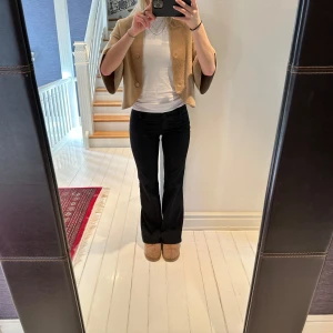 Lågmidjade svarta randiga kostymbyxor - Svarta lätt randiga utsvängda kostymbyxor. Låg midja. Liten 36 eller stor 34. PostNord spårbar frakt tillkommer på 67kr