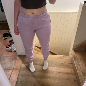 Ljuslila mjukisbyxor med resår - Säljer ett par ljuslila mjukisbyxor med resår i midjan och vid bensluten. Byxorna har en normal passform och är tillverkade i mjukt bomullsmaterial. Köptes på Gina Tricot. Perfekta för en avslappnad stil och har praktiska sidofickor.