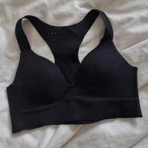 Svart sport-bh från Aim'n - Svart sport-bh från Aim'n med brottarrygg och ventilerande hål i ryggen. Tillverkad i ett stretchigt material med bred resår under bysten för extra stöd. 