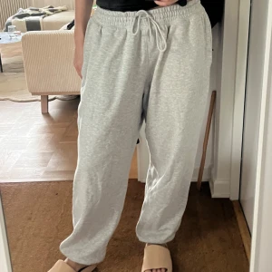 Grå mjukisbyxor med dragsko - Säljer ett par ljusgrå mjukisbyxor med resår och snörning i midjan. Byxorna har en avslappnad passform och är perfekta för chill dagar. Tillverkade i mjuk bomullsmix och har fickor på sidorna.