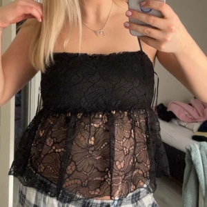 Svart spetslinne från Bikbok - Säljer ett svart linne från Bikbok med tunna axelband och vacker spets över hela toppen. Modellen är lätt utsvängd nedtill och har transparent spets med blommönster. Perfekt att styla med jeans eller kjol.