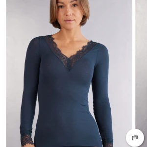 Marinblå långärmad topp med spetsdetaljer från intimissmi  - Säljer en marinblå långärmad topp med v-ringning och fina spetsdetaljer längs halsringningen och ärmsluten från intimissmi. I storlek m. Den är super mjuk i materialet och den funkar som en myströja. Har använt den ca 7 ggr. Säljer den pågrund av att den inte kommer till användning längre. Pris kan diskuteras.