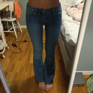 Blå bootcut jeans - Säljer ett par klassiska blå bootcut jeans med normal passform och låg midja. Jeansen har fem fickor, dragkedja och knapp framtill. Perfekta till vardags och lätta att matcha med olika toppar. Storlek 25 men väldigt stretchiga och stora i storleken!!