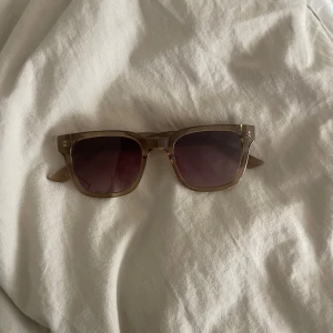 Bruna solglasögon med fyrkantig form - Snygga solglasögon med transparent brun båge och fyrkantiga glas. Glasen är mörka och ger en cool look, perfekt för soliga dagar. Passar dig som gillar stilrena accessoarer.