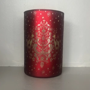 Röd ljuslykta med julmönster - En snygg ljuslykta i cylinderformad design med röd bakgrund och detaljerat  julmönster med renar och snöflingor. Perfekt att ha för en festlig touch.