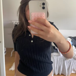  ribbad pikétröja - Säljer en mörkblå ribbad pikétröja med korta ärmar och klassisk krage. Tröjan har knappar framtill. Perfekt för en avslappnad och trendig look.