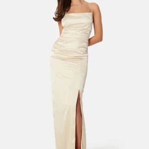 Champagnefärgad långklänning med slits och öppen rygg - Elegant balklänkng i champagnefärgad satin med smala axelband, slits framtill och öppen rygg med snörning. Klänningen har en figurnära passform och en stilren, minimalistisk look som passar perfekt till speciella tillfällen. Storlek 36, jag är 168. Använd en gång med original pris 899kr slut på hemsidan.