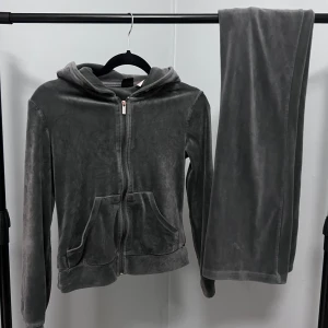 Mörkgrått mjukisset i velour - Mörkgrått mjukisset i velour. Tröja är i storlek XXS och saknar snören i huvan.  Byxorna är i storlek XS har vida ben och snörning i midjan. Byxorna och tröjan matchar perfekt i samma material för en avslappnad look.  Setet säljes i bra skick där skavanker kan förekomma.  Kommer från djurfritt hem. Paket skickas dagligen med korrekt emballage.