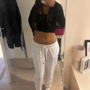 Vita mjukisbyxor från Nike - Säljer ett par vita mjukisbyxor från Nike med dragsko i midjan och klassisk logga på ena benet. Byxorna har en avslappnad passform och är perfekta för chill dagar eller träning. Superbekväma och stilrena!