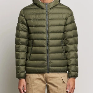 Olivgrön pufferjacka från Colmar - Säljer en olivgrön pufferjacka från Colmar med huva och dragkedja framtill. Jackan har två sidofickor med dragkedja och en diskret logotyp på ärmen. Perfekt för kyliga dagar.