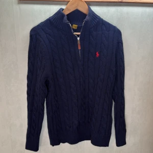 Mörkblå kabelstickad tröja från Ralph Lauren - Säljer en mörkblå Ralph Lauren 1/4 zip. Storlek M men kan va lite liten i storleken. Köpt för ungefär 2200kr.