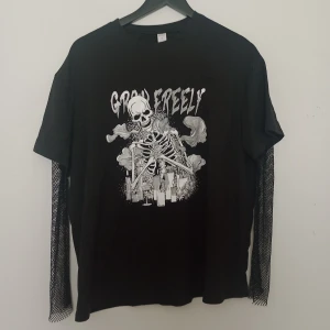 Svart långärmad t-shirt med skelettmotiv - Cool svart långärmad t-shirt från Romwe med tryck av ett skelett och texten 'Grow Freely' på bröstet. Ärmarna har ett unikt nätmönster som ger en edgy look. Perfekt för dig som gillar alternativ stil.