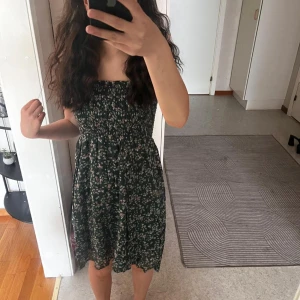 Grön blommig klänning från InWear - Supersöt grön klänning från InWear med små vita blommor. Klänningen är ärmlös, har smock upptil. Perfekt för varma dagar och enkel att styla med sneakers eller sandaler.🩴 