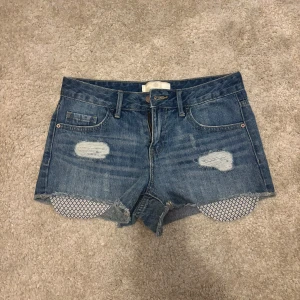 Blå jeansshorts från Pieces - Snygga blå jeansshorts från Pieces med råa kanter och slitna detaljer framtill med låg midja. Perfekta för varma dagar och enkel att matcha med olika toppar. PRIS KAM DISKUTERAS 