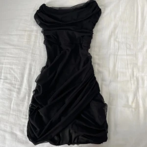 Svart tight klänning från Oh Polly - Säljer en svart tight klänning från Oh Polly med draperad design. Använd 1 gång så är i jätte bra skick!