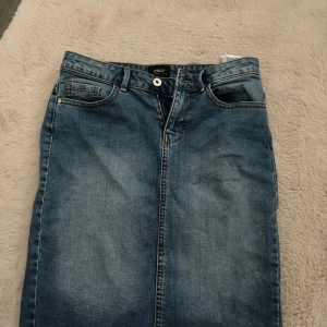 Jeanskjol från ONLY - Pris kan sänkas vid snabb affär. En blå jeans kjol ifrån only. Slutar precis ovanför knäna på mig. Kjolen har en slits baktilltill.