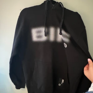 Brynäs hoodie  - Säljer en Brynäs hoodie med stort vitt tryck på bröstet. Tröjan har huva med dragsko och en stor magficka framtill. Perfekt för en avslappnad stil.