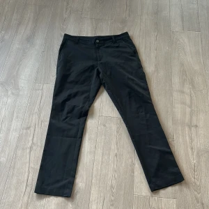 Svarta byxor från Puma - Svarta byxor från Puma med klassisk rak passform och broderad Puma-logga ovanför bakfickan. Byxorna har bälteshällor, knapp och dragkedja framtill samt två bakfickor. Perfekta för en sportig och stilren look. I princip helt nya växte lite snabbare än vad jag trodde 