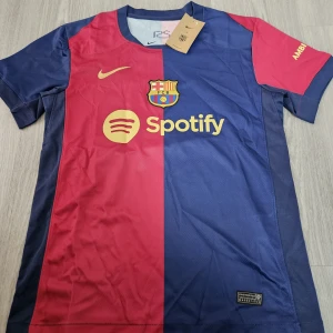 FC Barcelona Messi 10 matchtröja - Säljer en FC Barcelona fotbollströja med Messi 10-tryck. Tröjan är kortärmad, har klassiska blå och röda färger med klubbmärke, Nike-logga och Spotify som sponsor framtill. Materialet är lätt och andas, perfekt för fotboll eller support.