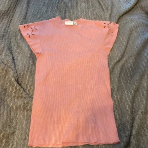 Rosa ribbad topp med broderade detaljer från Vila - Säljer en ljusrosa ribbad topp från Vila med korta ärmar och fina broderade blommönster på axlarna. Perfekt för vår och sommar, enkel att matcha till olika outfits.