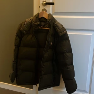 Svart dunjacka från Polo Ralph Lauren - Säljer en mörkgrön dunjacka från Polo Ralph Lauren som är i nyskick, storlek 14-16 år. Nypris ligger på 3229kr men säljs enbart för 2300kr. Hör av dig vid minsta fundering! Kan gå ner i pris vid snabb affär.