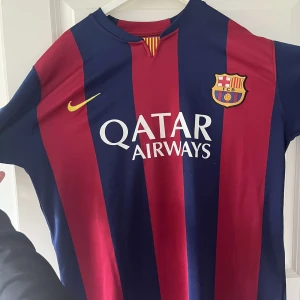 FC Barcelona Neymar Jr 11 matchtröja  - Säljer en klassisk FC Barcelona fotbollströja med Neymar Jr och nummer 11 på ryggen. Tröjan är kortärmad, har breda röda och blå ränder, Qatar Airways som sponsor på framsidan och Unicef-logga bak. Perfekt för dig som älskar Barca!