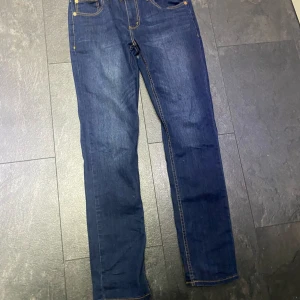 Levi's 512 Slim jeans blå. Storlek 176cm  - Säljer ett par klassiska blå Levi's 512 Slim jeans med raka ben och gul kontrastsöm. Jeansen har fem fickor, knapp och dragkedja framtill samt Levi's ikoniska läderpatch bak i midjan.