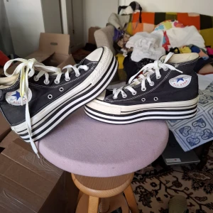 Svarta Converse sneakers med platåsula - Säljer ett par svarta Converse All Star sneakers med vit platåsula och klassisk logga på sidan. Skorna har vita snören och svart-vita ränder på sulan för en cool look. Perfekta för dig som vill sticka ut lite extra.