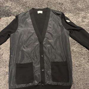 Moncler Cardigan - Säljer en skit snygg svart cardigan från Moncler, den har inga defekter och är i storleken M. Perfekt för sommarkvällar då den är ganska tunn. Den är så klart äkta! Priset är 1800. Hör av er vid eventuella frågor