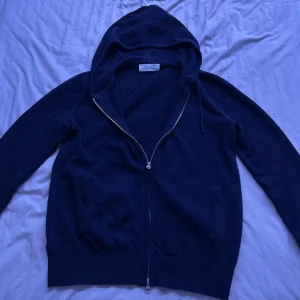 Sayless hoodie - Säljer en stilren mörkblå hoodie med dragkedja och huva. Perfekt för kyliga dagar. Den har långa ärmar och en bekväm passform. Ett måste i garderoben för en avslappnad look.