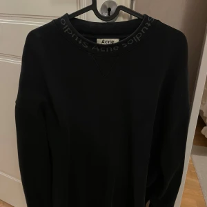 Svart tröja från Acne Studios - Svart tröja från Acne Studios med rund halsringning och diskret logga på kragen. Storlek S. (Använder INTE köpdirekt funktionen) 