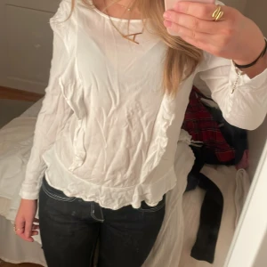 Vit långärmad blus med volangdetaljer - Säljer en stilren vit blus med långa ärmar och volangdetaljer längs sidorna och nederkanten. Den är lite skrynklig på bilderna, men det går enkelt att fixa när man tvättar eller stryker den💕 använd ett par gånger, men inga defekter. Säljer då den blivit för liten💗
