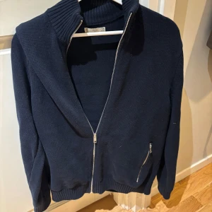 Mörkblå stickad tröja från MNG - Säljer en stilren mörkblå stickad tröja från MNG med dragkedja framtill. Perfekt nu i vår och sommarkvällar. Skriv privat vid frågor eller funderingar!