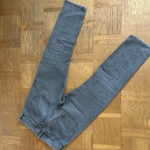 Grå jeans från H&M - Säljer ett par grå jeans från H&M i relaxed fit. De har en klassisk design med fem fickor och en dragkedja. Perfekta för en avslappnad stil.