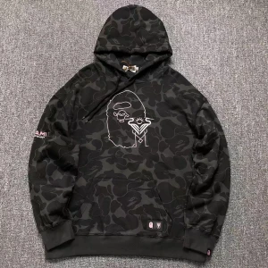 Svart BAPE hoodie - Säljer en cool svart hoodie med camouflagemönster från A Bathing Ape. Den har ett unikt broderi på framsidan och en justerbar huva. Perfekt för dig som vill sticka ut!