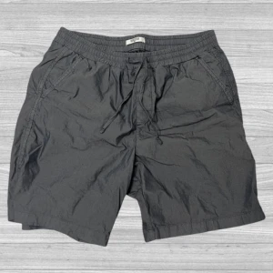 MudoFTS64 - Snygga grå shorts från MudoFTS64 med elastisk midja och snörning för extra komfort. Perfekta för en avslappnad stil. De har praktiska sidofickor och en bakficka.