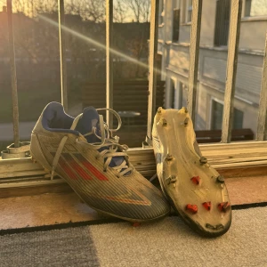 Adidas F50 Academy  - Säljer ett par fotbollsskor i blått och rött med snörning. Skorna har dobbar för bra grepp på planen och en sportig design. Perfekta för fotbollsträning eller match. Skick 7/10 