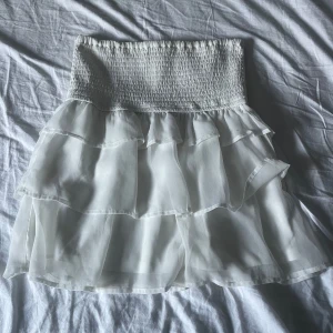 Vit volangkjol från BikBok - Säljer en söt vit volangkjol från BikBok i storlek XS. Kjolen har flera lager av volanger och en elastisk midja för en bekväm passform. Perfekt för sommarens alla tillfällen! 🌸