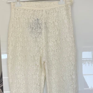 Vita spetsbyxor nya - Säljer ett par eleganta vita byxor i spetsmaterial. De har en hög midja och en rak passform som ger en stilren look. Perfekta för en somrig outfit eller en speciell tillställning. Gräddvit , fodrade , hög midja 72-74 cm 