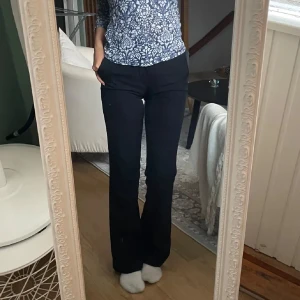 Svarta kostymbyxor - Snygga svarta kostymbyxor med en klassisk design. Byxorna har en bootcut passform och är perfekta för en stilren look. De har en diskret dragkedja och knapp framtill.