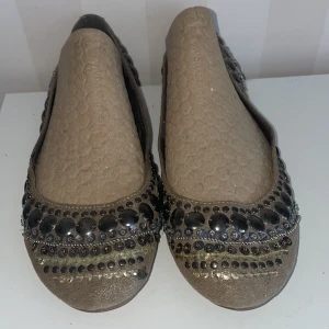 Beige ballerinaskor med paljetter nya - Snygga beige ballerinaskor dekorerade med glittrande paljetter och stenar , nya, pga förvar läder inuti släppt, inget som syns eller märks när man har de på.Perfekta för att ge en touch av glamour till din outfit. Skorna har en rund tå och en bekväm passform.