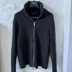 Brand Island Cardigan  - Säljer en svart cardigan från Brand Island i Göteborg i storlek M. Tröjan är köpt januari 2025 för ett nypris av 999 kr. Kvitto medföljer.  Modell: “MARCELLO ZIP KNIT”