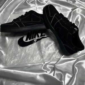 JORDAN 1 RETRO LOW OG SP TRAVIS SCOTT B... - JORDAN 1 RETRO LOW OG SP TRAVIS SCOTT BLACK PHANTOM. helt nya,snygga svarta sneakers från Nike med vit kontrastsöm och klassisk logga. Skorna har en låg profil och snörning framtill. Perfekta för en stilren look.